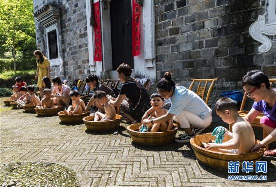 在湖北省秭归县屈原故里景区端午习俗馆，家长为孩子洗艾叶浴。