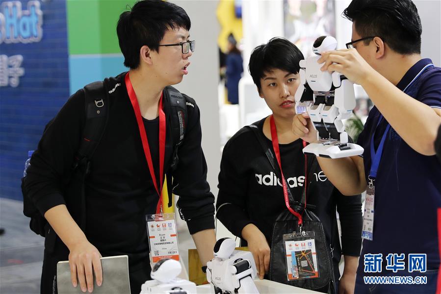 10月16日，一名工作人员（右）向参观者介绍一款机器人产品。 当日，2018中国婴童展在上海新国际博览中心开幕。 新华社记者 方喆 摄
