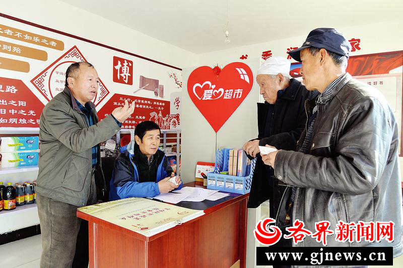 盘峰村第一书记韩秀高向贫困户介绍爱心积分如何在爱心超市兑换生活用品