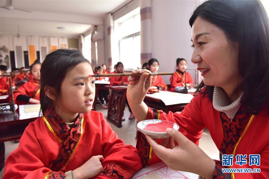 　3月8日，在河北石家庄新乐市实验小学举行的开笔礼仪式上，老师为学生额头点朱砂。 当日是农历二月初二，各地举办丰富多彩的民俗活动。 新华社发（贾敏杰 摄）