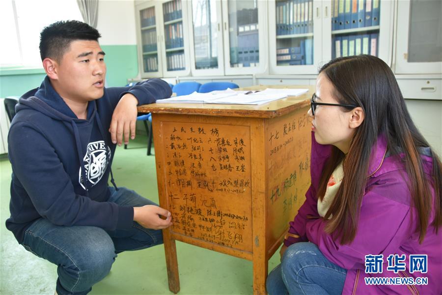 　复旦大学第二十届研究生支教团队长杨陈浩彤给记者介绍写有前十九届支教队员名字的课桌（4月23日摄）。 1999年至今的20年间，复旦大学研究生支教团的224名队员先后赴宁夏固原市西吉县的9所乡镇中学支教。支教队员翻过崇山峻岭，用青春和汗水在这片贫瘠的土地上播下求知进取的种子。 新华社记者 卢鹰 摄