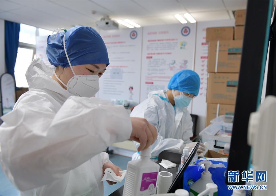 　佘沙（左）在湖北省人民医院东院病区的清洁区防护操作间内协助做准备的同事（2月23日摄）。　新华社记者李贺摄