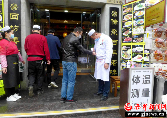 3月17日，市民在西安回坊风情街一家餐馆进餐前扫码测温。 