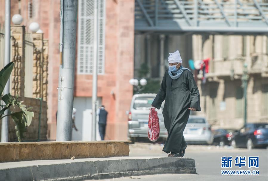 4月19日，在埃及首都开罗, 一名戴口罩的行人从街头走过。新华社记者 邬惠我 摄