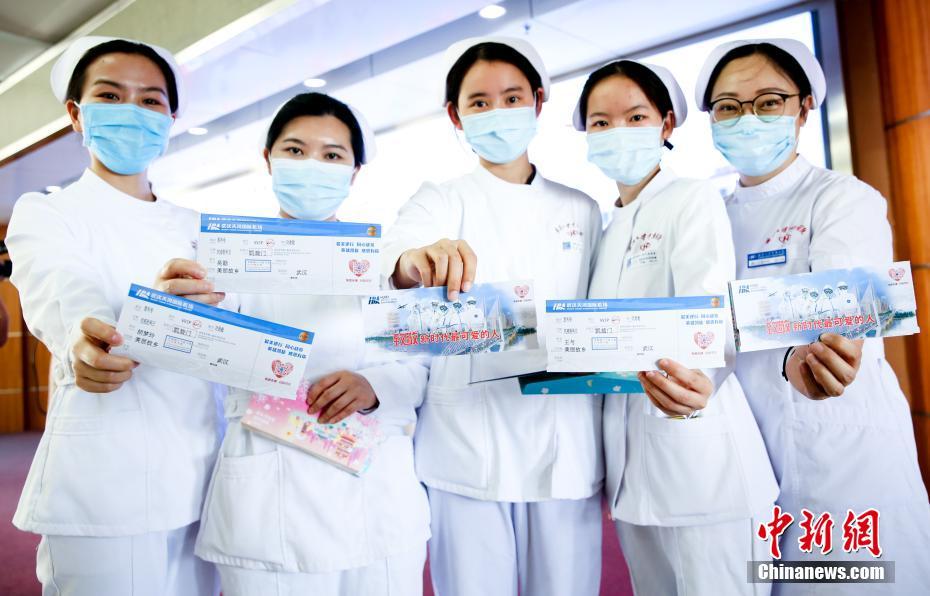 5月12日，在国际护士节当天，湖北机场集团工作人员为武汉大学中南医院的5位护士送上一份特别的节日礼物——以她们合影为原型的抗疫纪念登机牌。图为抗疫纪念登机牌原型中南医院的5名护士展示登机牌。 中新社记者 张畅 摄