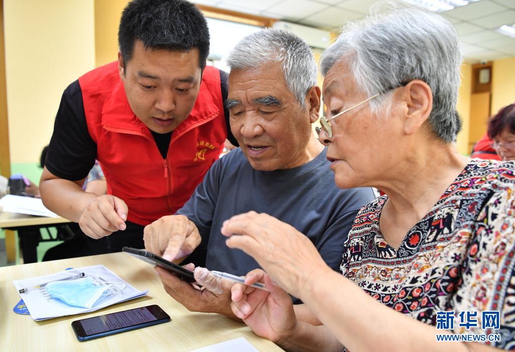 6月15日，在咸阳市小桔灯公益服务中心的教室，志愿者教学员使用智能手机的基本功能。
