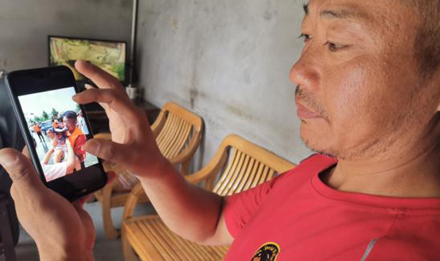 河南抗洪救灾现场，陕西救援人员用嘴咬着衣服给婴儿遮阳