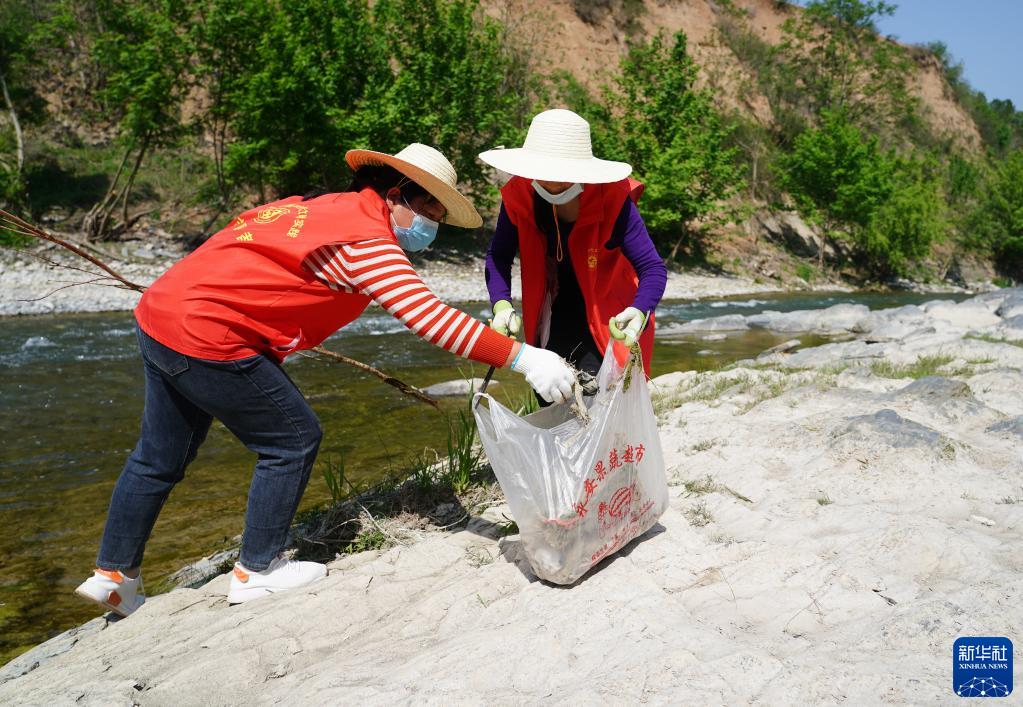 4月10日，女子志愿护河队队员在陕西旬阳市双河镇高坪社区河边捡拾垃圾。