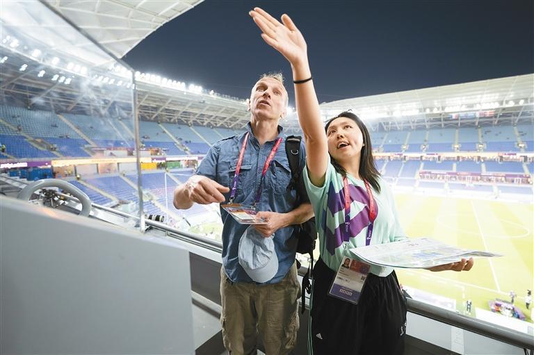11月26日，志愿者白鑫沂（右）在多哈974球场看台为媒体做引导。