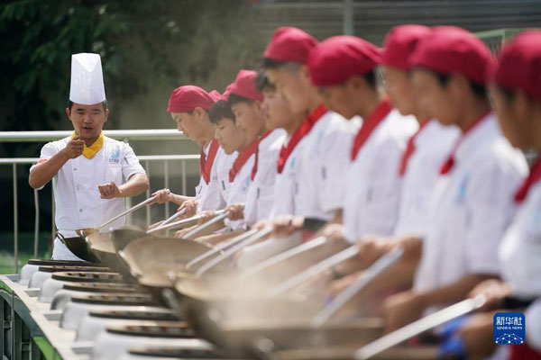 6月25日，在位于西安市蓝田县的蓝田厨师学校，教师成晓强（左一）指导学生们练习翻勺。新华社记者 李一博 摄