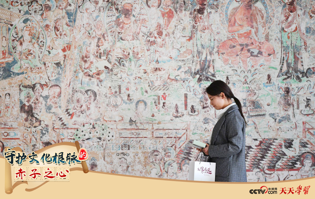 2023年4月25日，敦煌研究院文物数字化保护团队创意营销人员廖雪婷从一幅高保真复制壁画前走过。