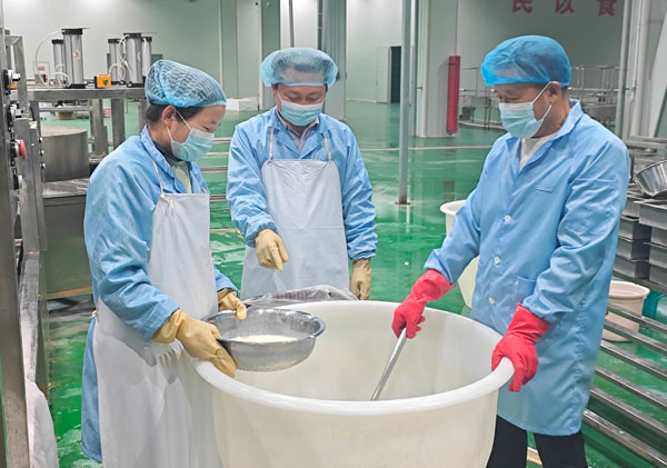 洛南县豆农食品科技有限公司生产部负责人王齐（中）和工友试做内脂豆腐。